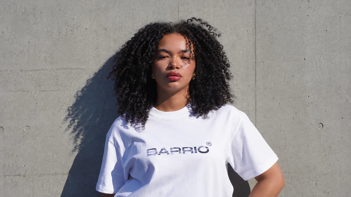 Model in a white Barrio tee against a concrete wall